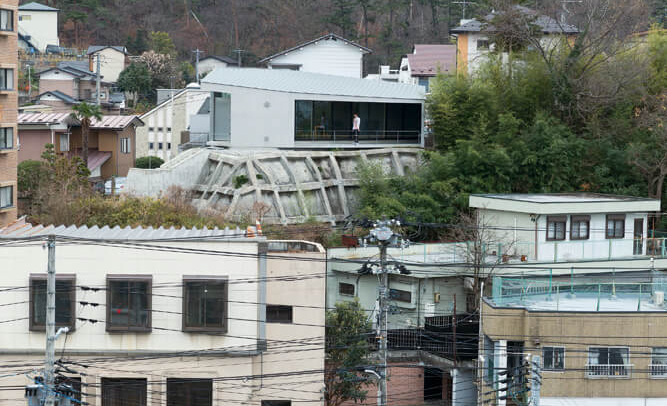 擁壁の上にオブジェのように建つ平屋・土地と建物に不思議な一体感がある