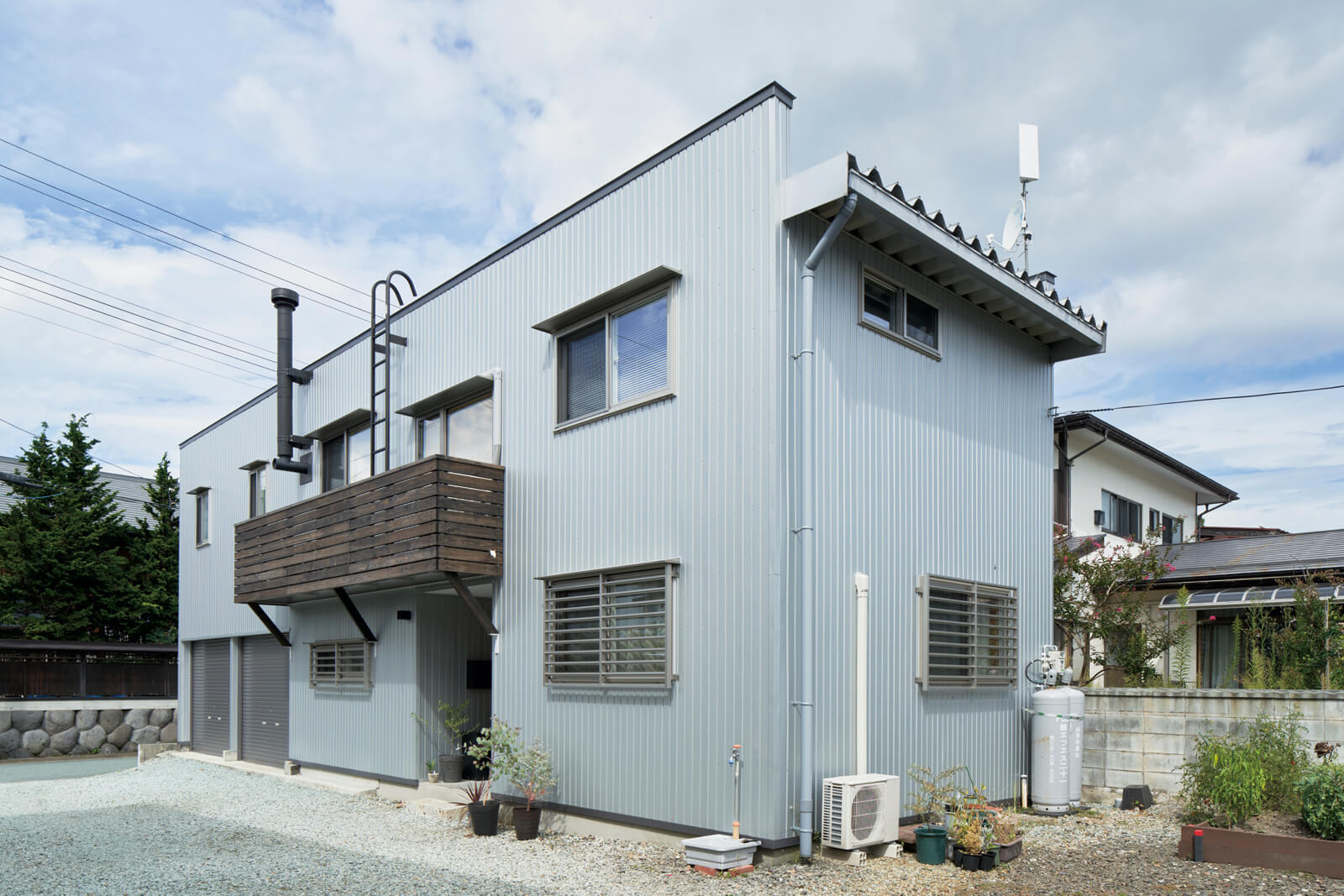 リノベーションで、Nさん家族が使いやすい住宅に。軒の出がないので、雨や雪でも汚れにくくメンテナンスもしやすいよう、外壁はガルバリウム角波貼りを採用。新たにベランダをつくり、煙突掃除のためのはしごも設置した