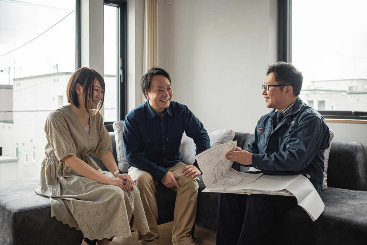 大開口を設けた明るいリビングで、家づくりを振り返るYさん夫妻と営業部の戸村公平さん。「好みがはっきりしていて、センスの良いご夫妻とのプランづくりはいつも楽しく、スムーズに進みました」と、戸村さん