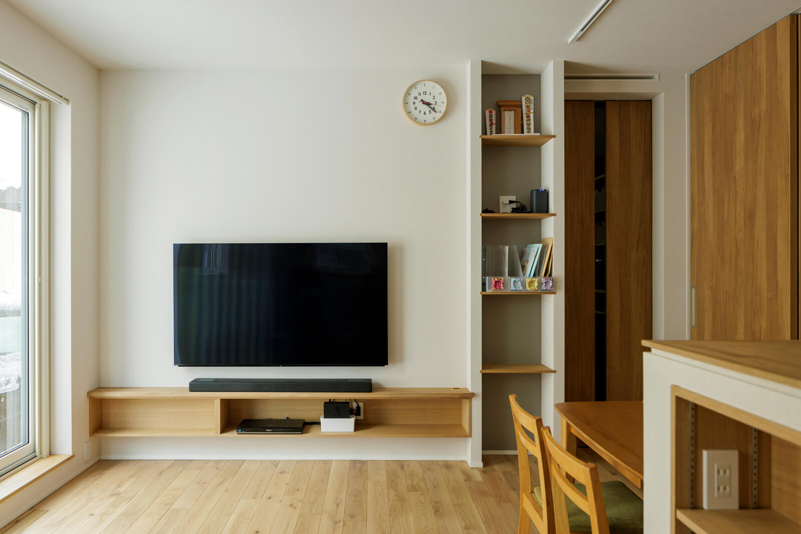 ホコリになりやすいテレビやチューナー類の配線を壁の中に隠せるつくりにし、テレビの下に横長のオープン収納を造作。テレビ横の収納は、子どもたちが持ち帰るプリント類がおける奥行きで造りつけた。LDKの出入り口には、KAMIYAのフルハイトドアを採用した