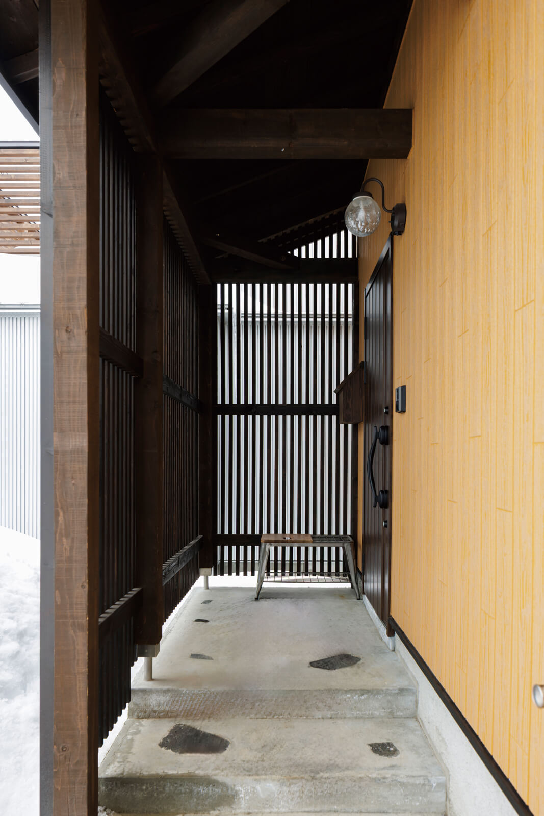 温かみのある木製のルーバーで囲った玄関ポーチ。風雪の吹き込みを和らげるとともに、外部からの目線を遮る役割も