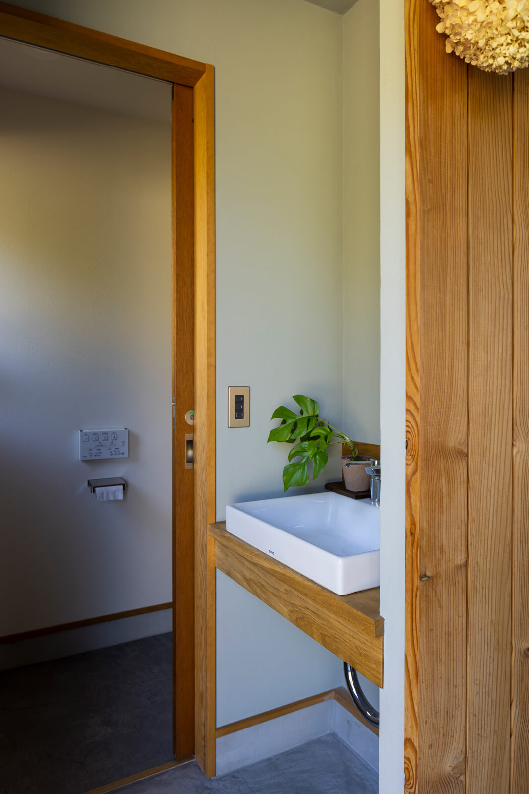 店舗の造作手洗いとトイレにも、木をふんだんに用いた。カラマツ無垢材の色が際立つよう、店舗の壁はグレーの珪藻土で仕上げた