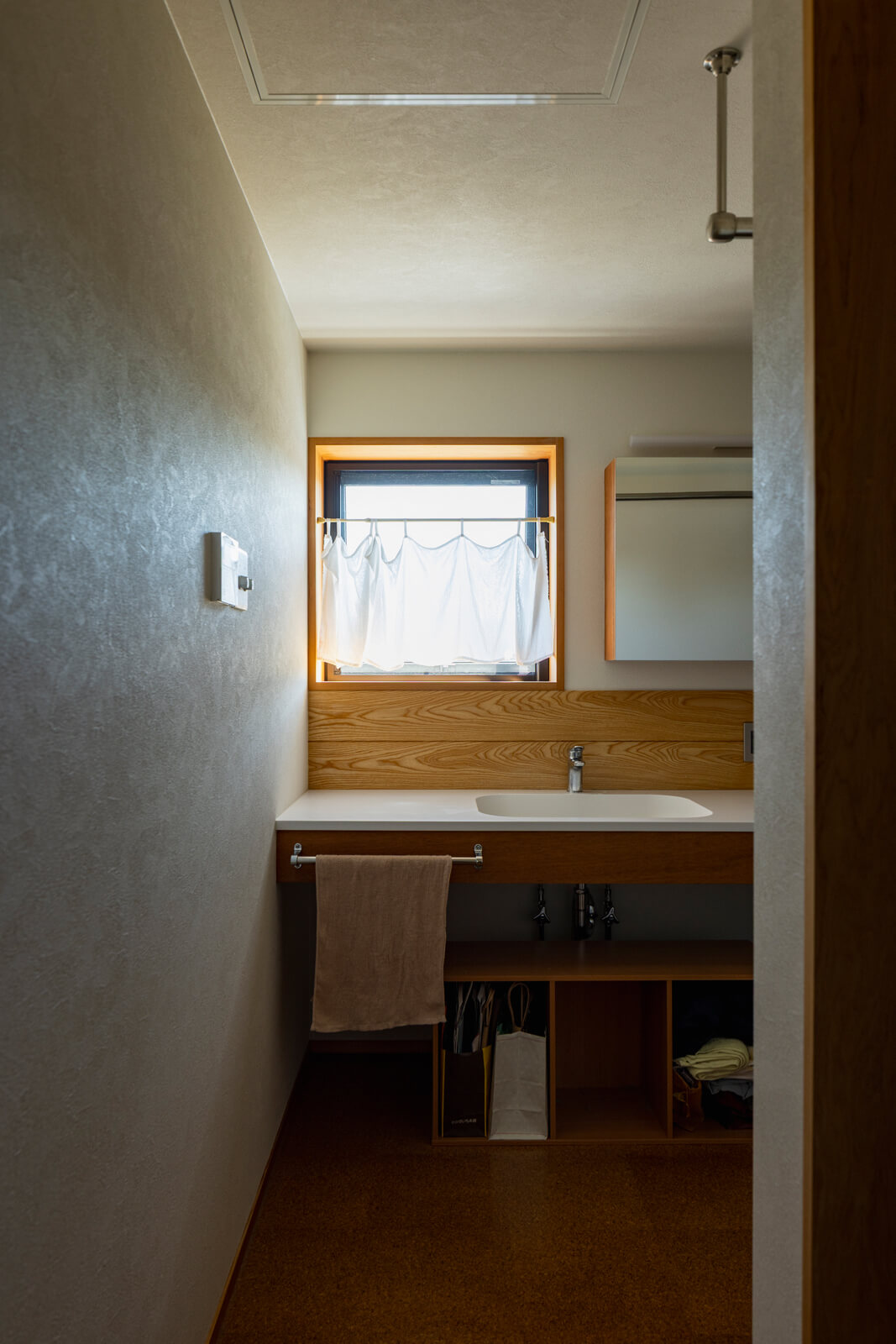 ワイドスパンの造作洗面台を設えた2階ユーティリティは、洗濯室も兼ねる。右手手前は、浴室