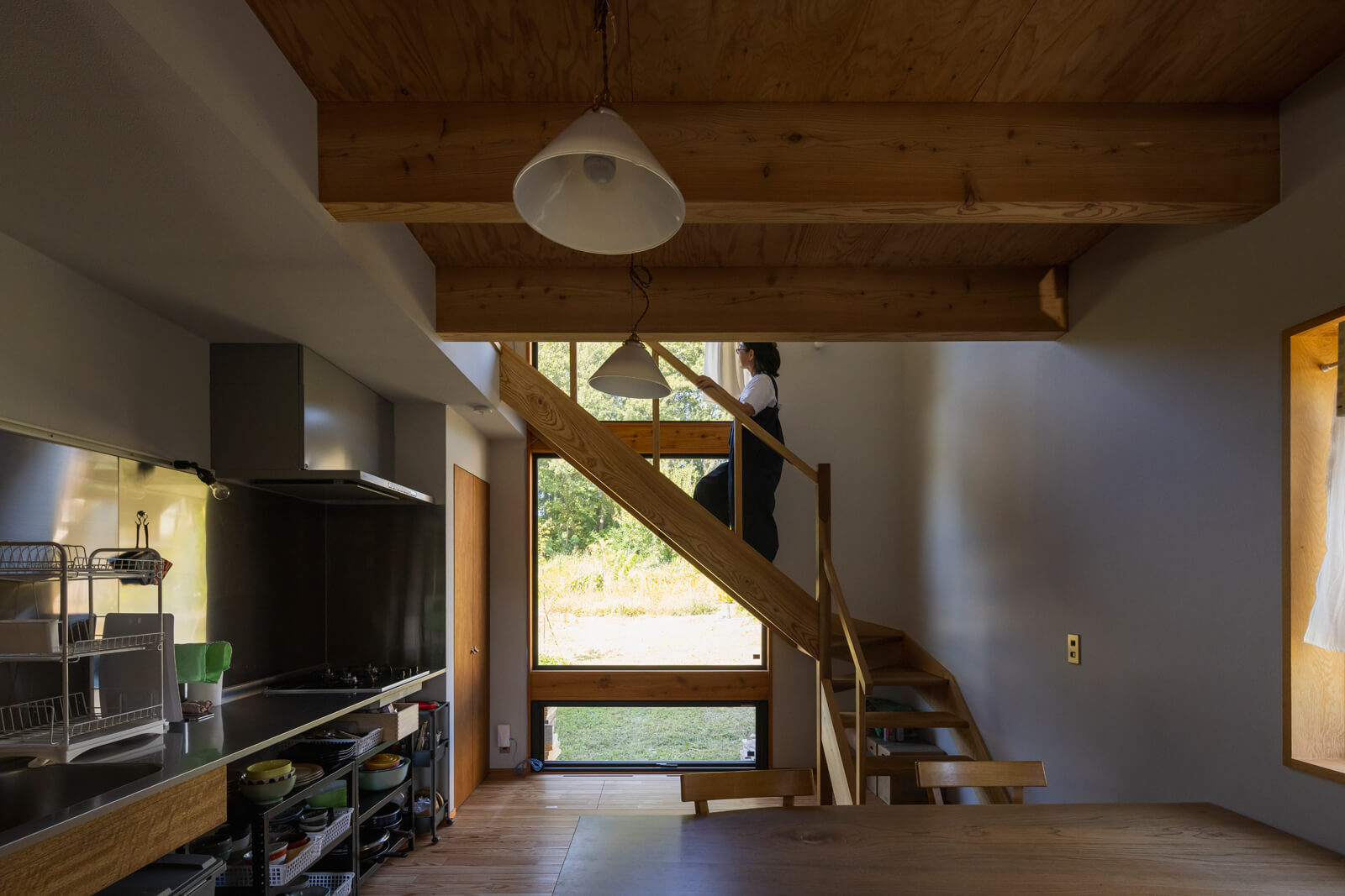 現しの梁にガイシ配線を採用したダイニングキッチン。住まい手の使い勝手に柔軟に寄り添えるよう、キッチンの設備も最小限に留めた