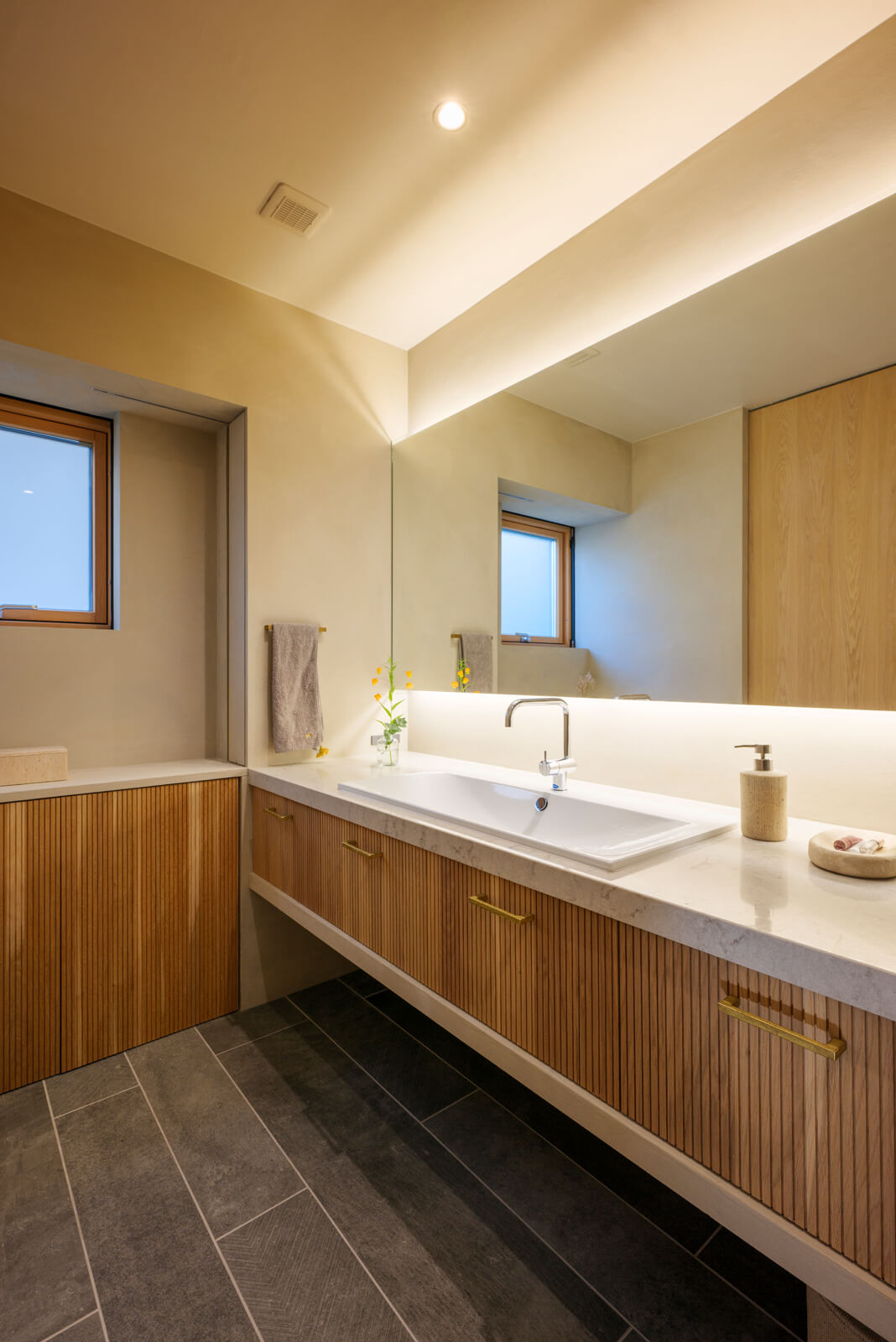 洗面室は奥さんのメイクルームも兼ねる。さり気ないけれど大容量の収納棚が設置されているため、物が多くなりがちな洗面室もスッキリ。床には水に強いタイルを使用した