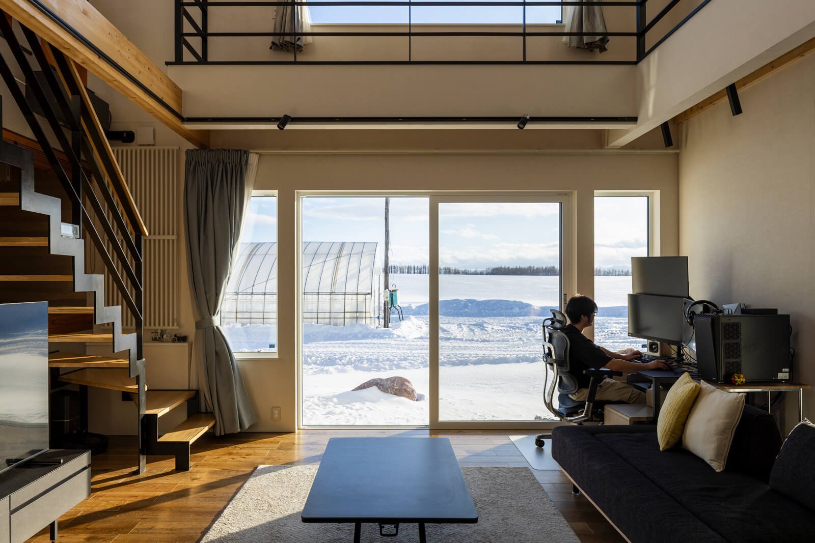 大きな窓から畑と日高の山並みを一望できるリビング。天気のいい日は、すのこ状のキャットウォークからも陽射しが降り注ぎ、厳冬期も暖かく過ごせる