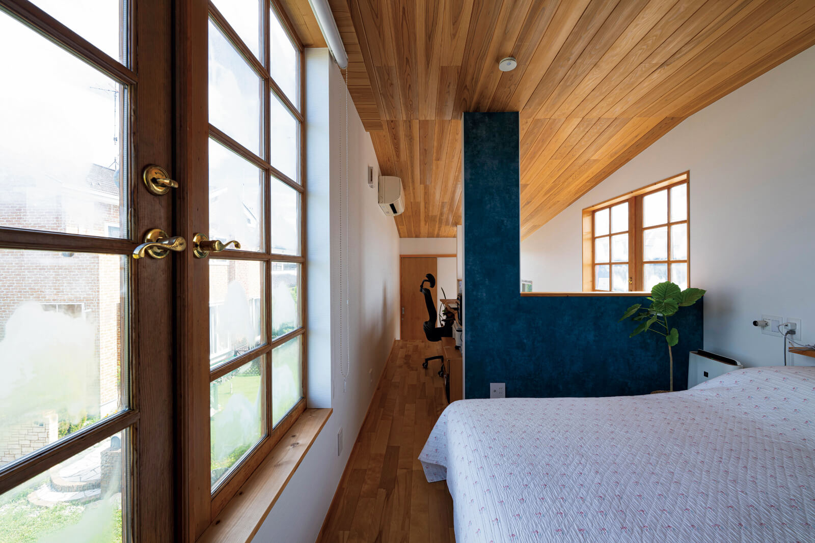 2階はトイレと浴室以外に扉のないワンルームの間取り。北面の窓からの安定した光が寝室を包む。ネイビーブルーのクロスが空間のアクセントに