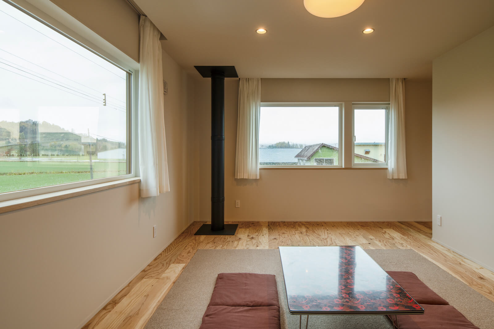 周囲の緑の風景を取り込む窓をL字に配した2階のセカンドリビング。階下の薪ストーブの煙突から伝わる薪火の熱が、開放的な空間をほんのりと暖める