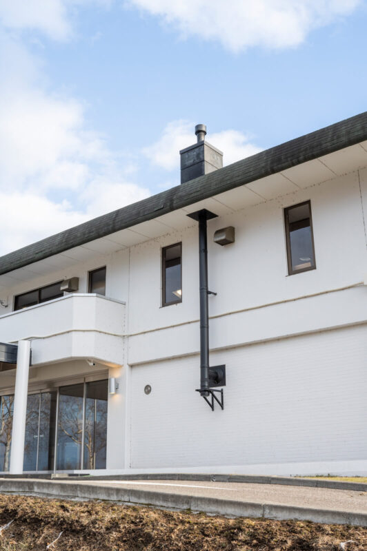 薪ストーブの設置場所を壁側に寄せて煙突を壁出しとすることで、施工にかかるコストを最小限に