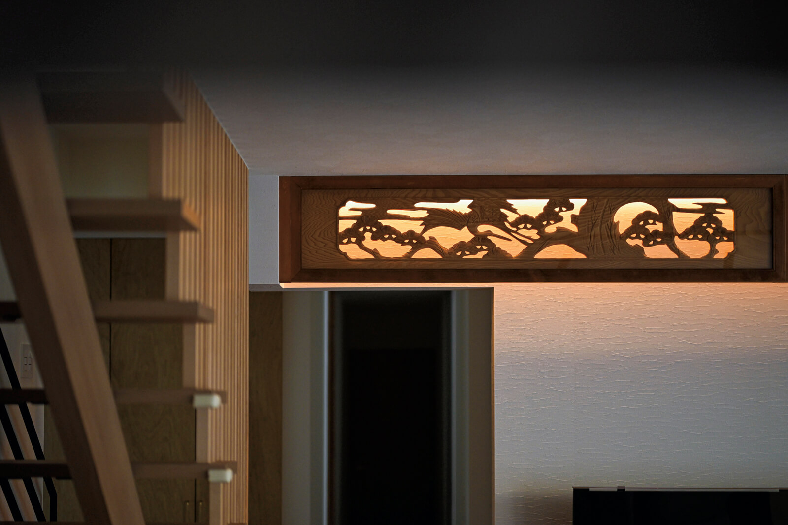 和室に使われていた欄間をリビングで活用。間接照明で彫刻が映え、家族の集まる空間でこれまで以上に存在感を増している