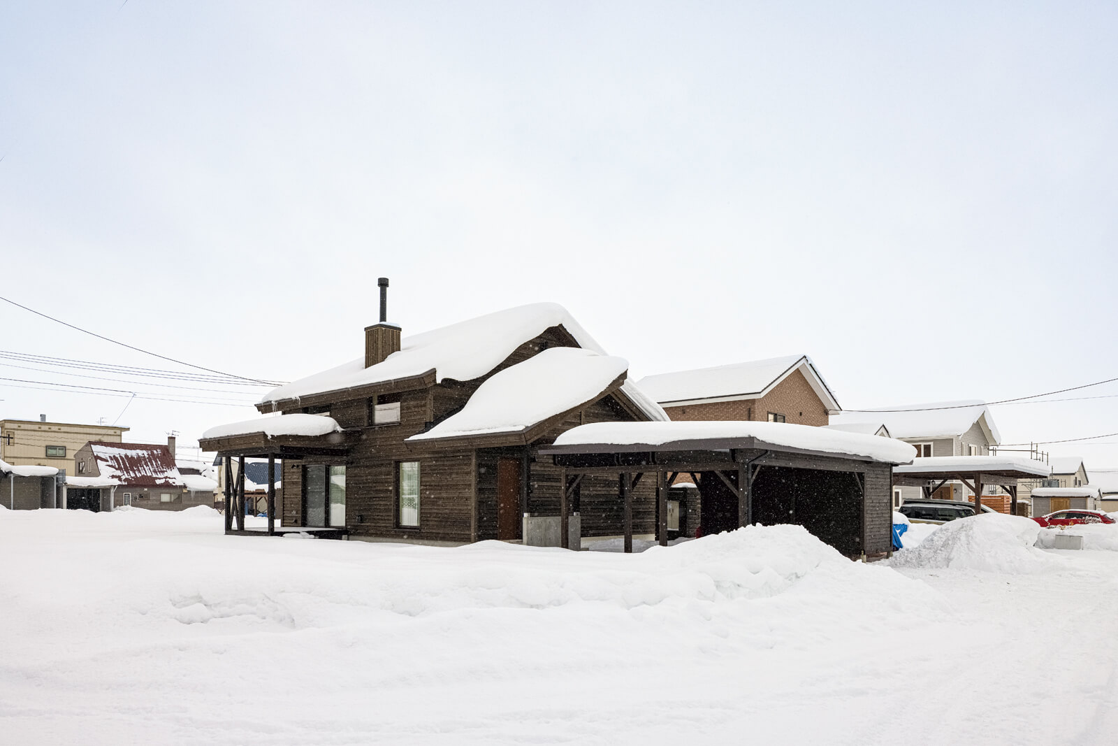 屋根勾配などを地域の基準に合わせて計画した外観。道南スギ横張りの外壁が東川町の風景と調和する落ち着いたたたずまい