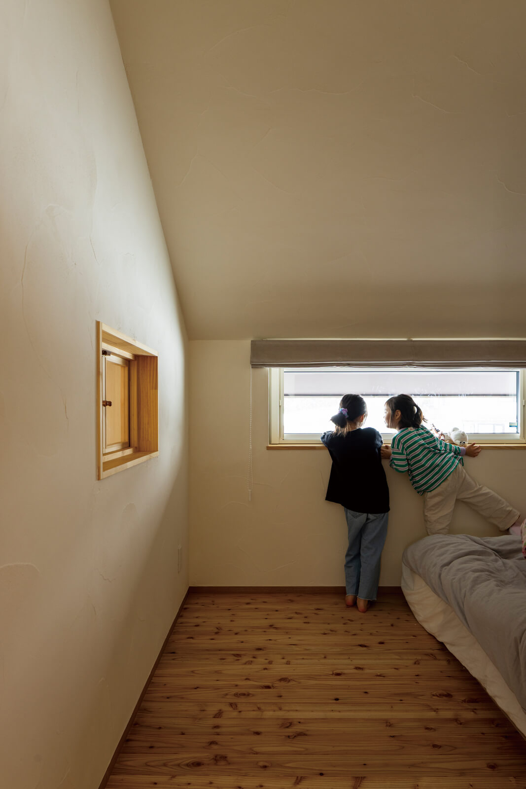 寝室はシンプルにまとめた安らぎのある空間。景色を切り取る横長窓と吹き抜けにつながる小窓から、やわらかな光が射し込む